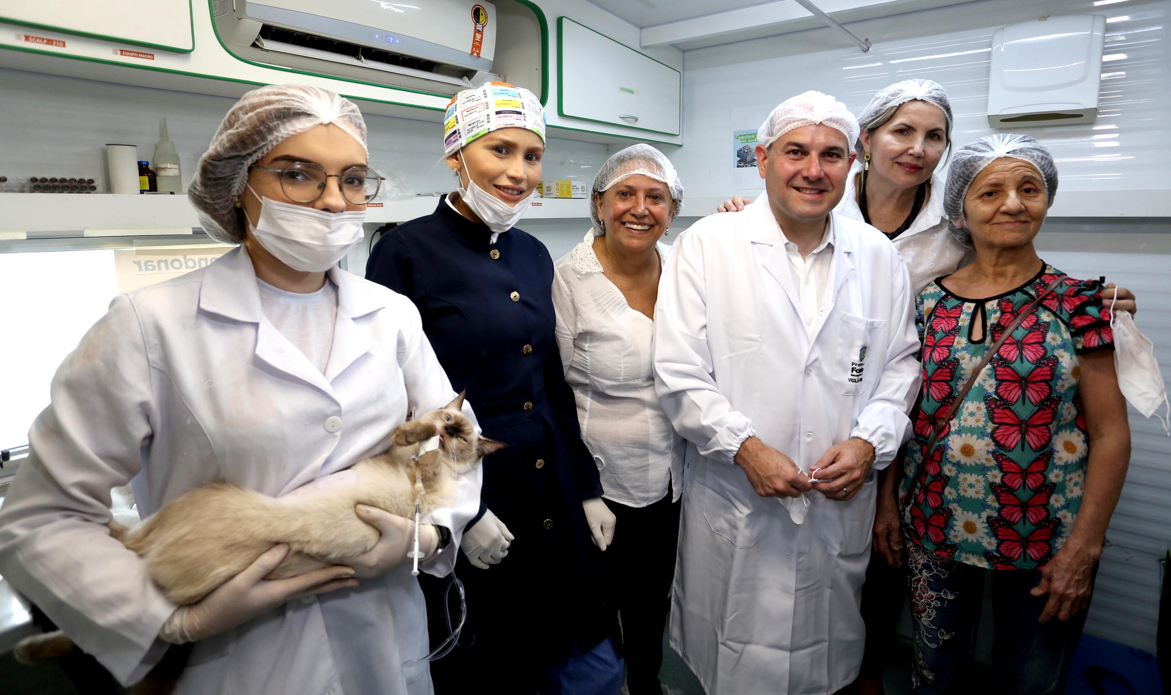 prefeito de jaleco ao lado de veterinária segurando gato no colo e outras pessoas ao lado posando para a foto